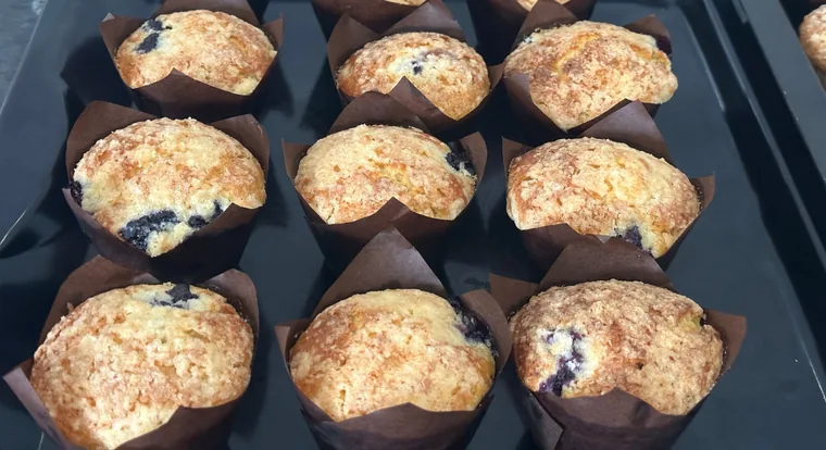 Blueberry muffins in brown tulip liners on a baking tray