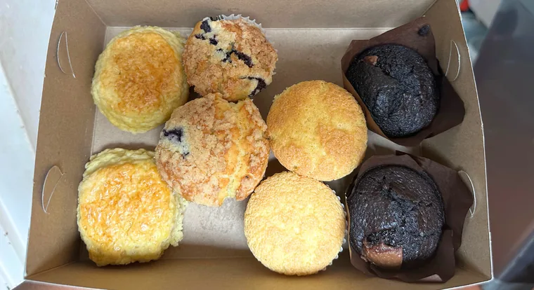 Six golden and dark muffins nestled in a kraft box