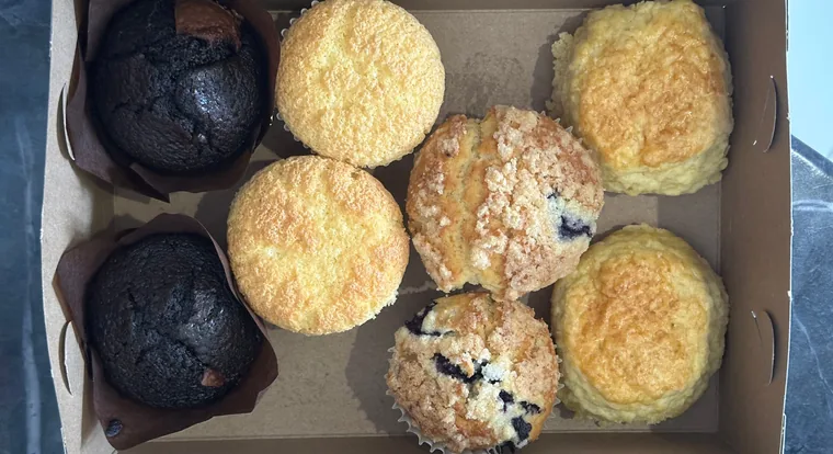 Six muffins boxed up, chocolate, corn and blueberry