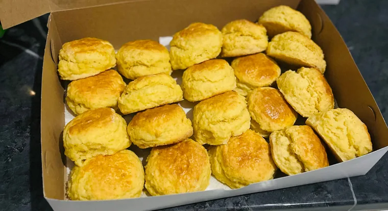 A box filled with warm golden scones, ready to go